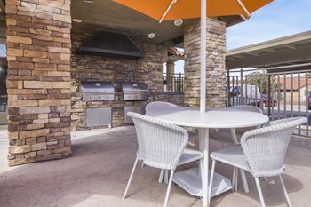 a patio with a table and chairs and a barbecue grill
